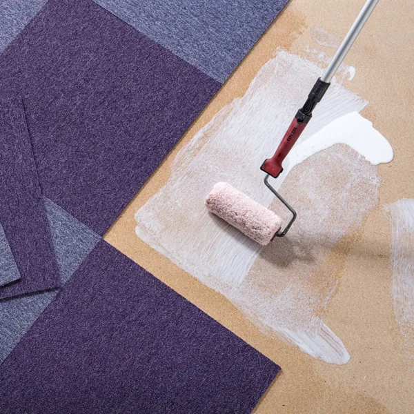 Applying adhesive with a roller for purple carpet tiles.