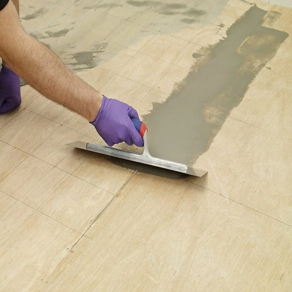 Applying floor leveler for carpet tile surface preparation.