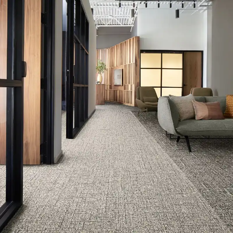 Light-colored patterned carpet in a modern office hallway.